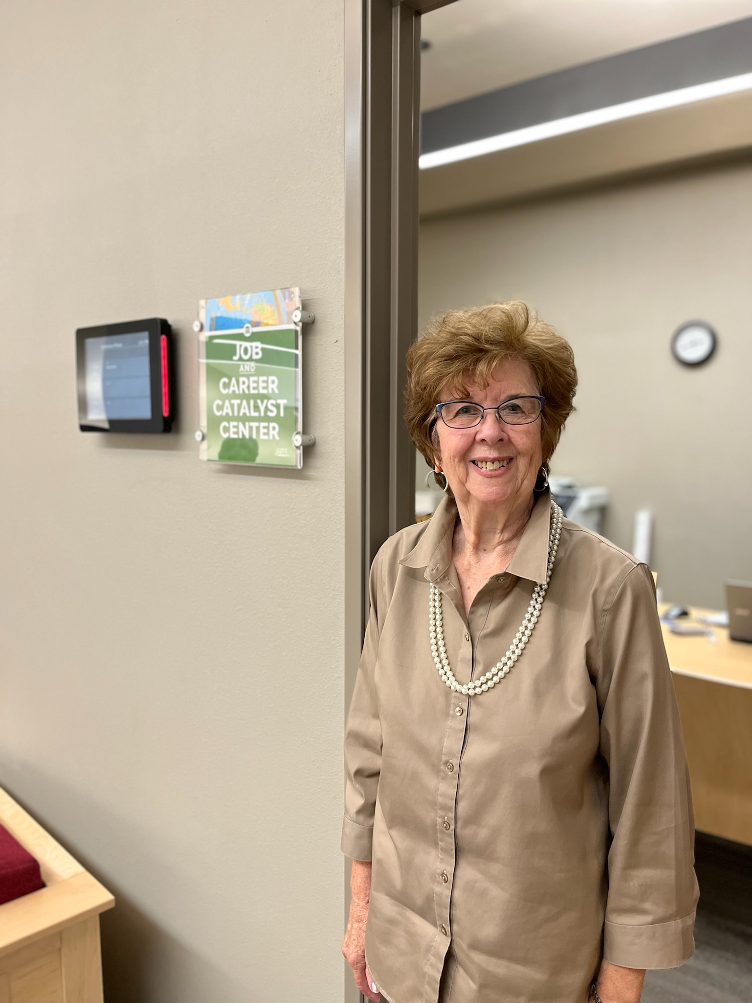Job and Career Coach Bev Rhoades in tan shirt standing outside conference room