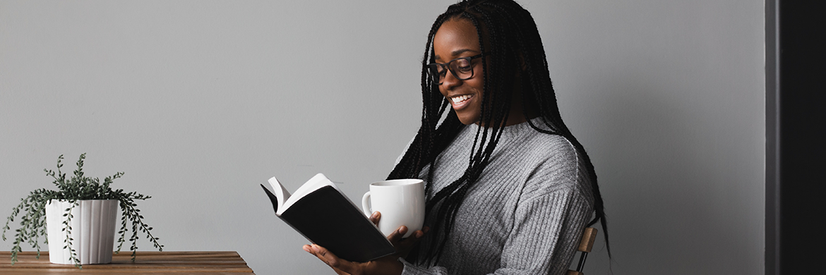 Woman Reading book with coffee cup in hand