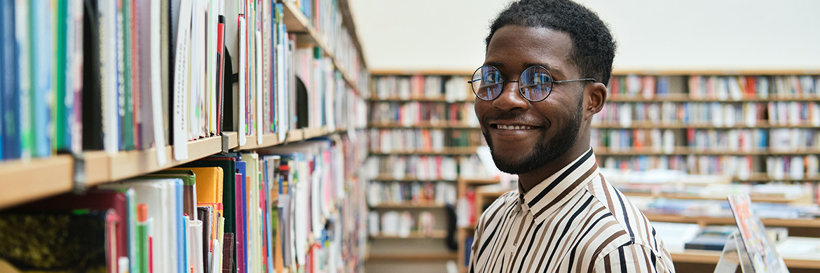 Young man shelving books in the library