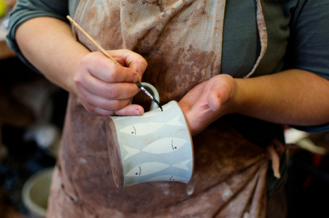 person painting a pottery cup