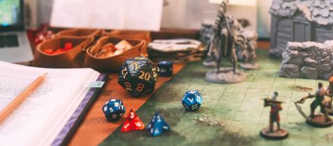 table with D&D pieces and dice on a playing board